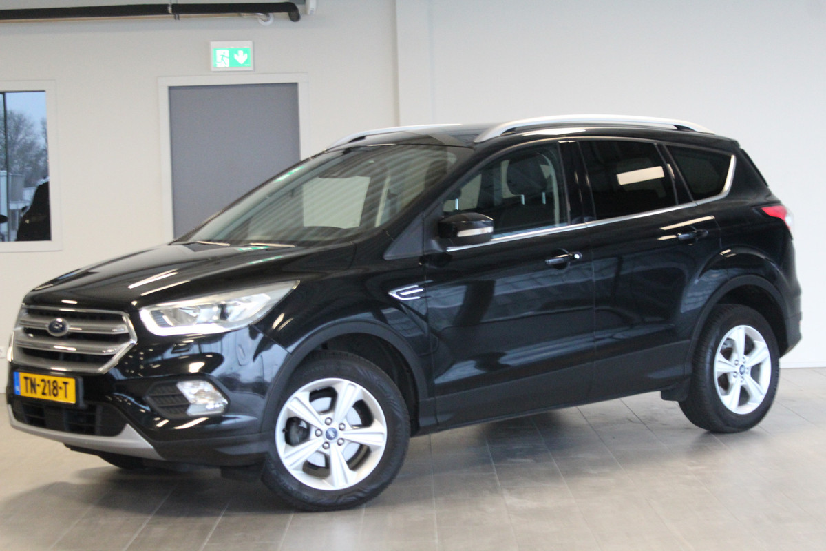 Ford Kuga 1.5-150pk EcoBoost Titanium. Nette Ford Kuga met een trekgewicht van maar liefst 2.000kg ! Autm. airco, stoel-, stuur- en voorraamverw., camera, parkeersensoren achter, navigatie, telefoonvoorb.,  17"LM wielen+all season banden, trekhaak, adapt. cruise cntrl etc.
