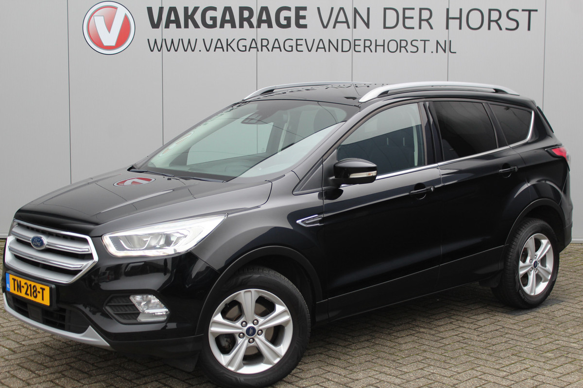 Ford Kuga 1.5-150pk EcoBoost Titanium. Nette Ford Kuga met een trekgewicht van maar liefst 2.000kg ! Autm. airco, stoel-, stuur- en voorraamverw., camera, parkeersensoren achter, navigatie, telefoonvoorb.,  17"LM wielen+all season banden, trekhaak, adapt. cruise cntrl etc.