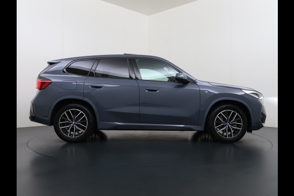 BMW iX1 eDrive20 67kWh M Sport pakket Pano-Dak/Schuif-dak Leer SOH 100% Warmtepomp Camera Navi Ecc PDC-a+v Apple Carplay Android Auto Elek.Achterklep Zwarte-Hemel VerkeersbordHerkenning WiFi M Aerodynamica  Lmv Led Privacy Glas Isofix DAB Keyless Wifi 1e Eigenaar Origineel Nederlandse Auto !!