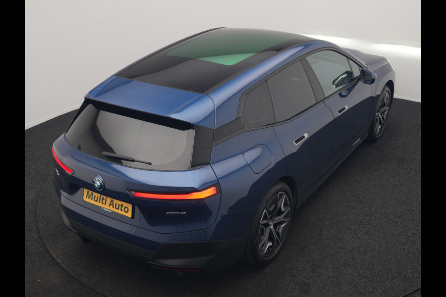 BMW iX xDrive40 Excellence 77 kWh 327pk | SOH 96,9% | Trekhaak Af Fabriek | Panodak Sky Lounge | Adaptive Cruise | Head Up | 360 Camera | Harman / Kardon | Lederen Sportstoelen & Stuur Verwarmd | Sfeerverlichting | BLIS | Keyless |