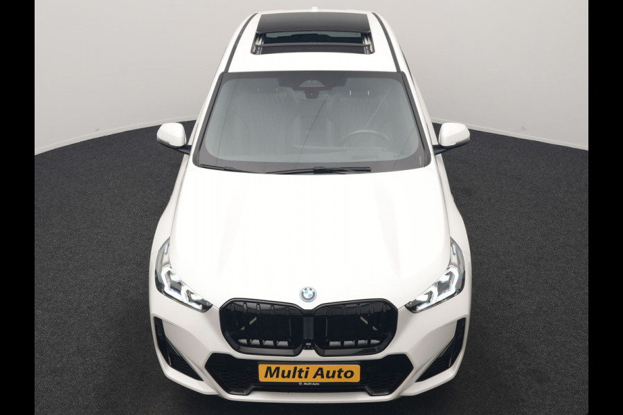 BMW iX1 xDrive30 M Sport 313pk Dealer O.H. | Trekhaak Af Fabriek | Panodak | 360 Camera | Head Up | Lederen Sportstoelen Memory & Verwarmd | Stuur Verwarmd | Keyless | BLIS | Sfeerverlichting | Apple Carplay | Navigatie | DAB | 20"L.M
